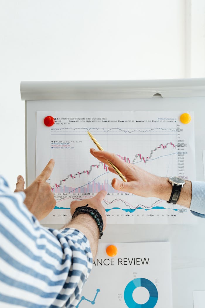 Services Two people analyzing financial charts on a whiteboard during a business meeting.
